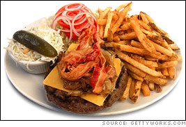 A bacon cheeseburger with the works with a side of fries, coleslaw, and a pickle