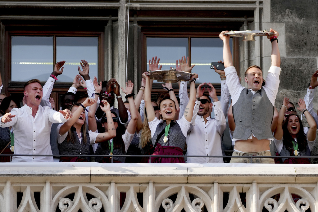FC Bayern Munich's women team captain Lina Magull, left, and FC Bayern Munich's men team captain Manuel Neuer, right, lift the trophys besides their teammates on the balcony of the town hall at Marienplatz square in Munich, Germany, Sunday, May 28, 2023 during a ceremony to celebrate winning the German women's and men's soccer championships.