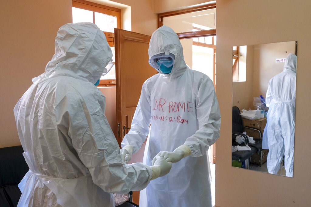 Doctors wearing protective equipment pray together before they visit a patient who was in contact with an Ebola victim