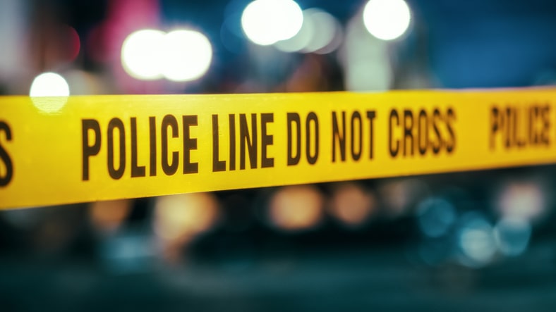 Yellow Tape Showing Text Police Line Do Not Cross Restricting a Crime Scene Area At Night.